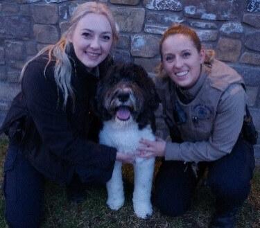 Two CSOs posing with a dog