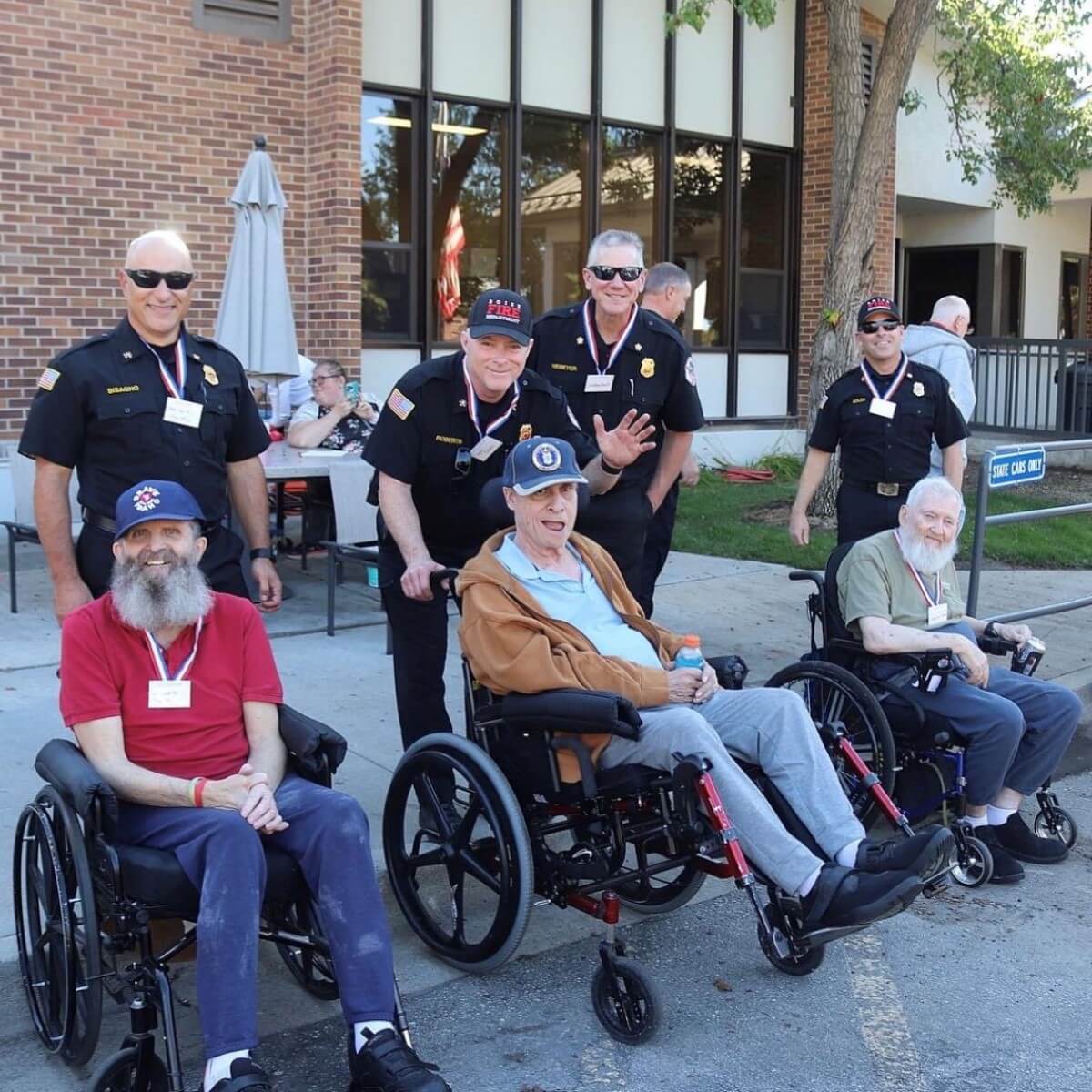 Group of firefighters standing next to several people who use wheelchairs.