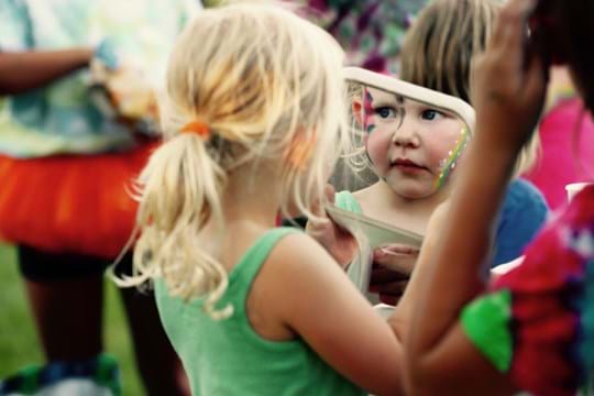 Little girl looking at facepaint in the mirror