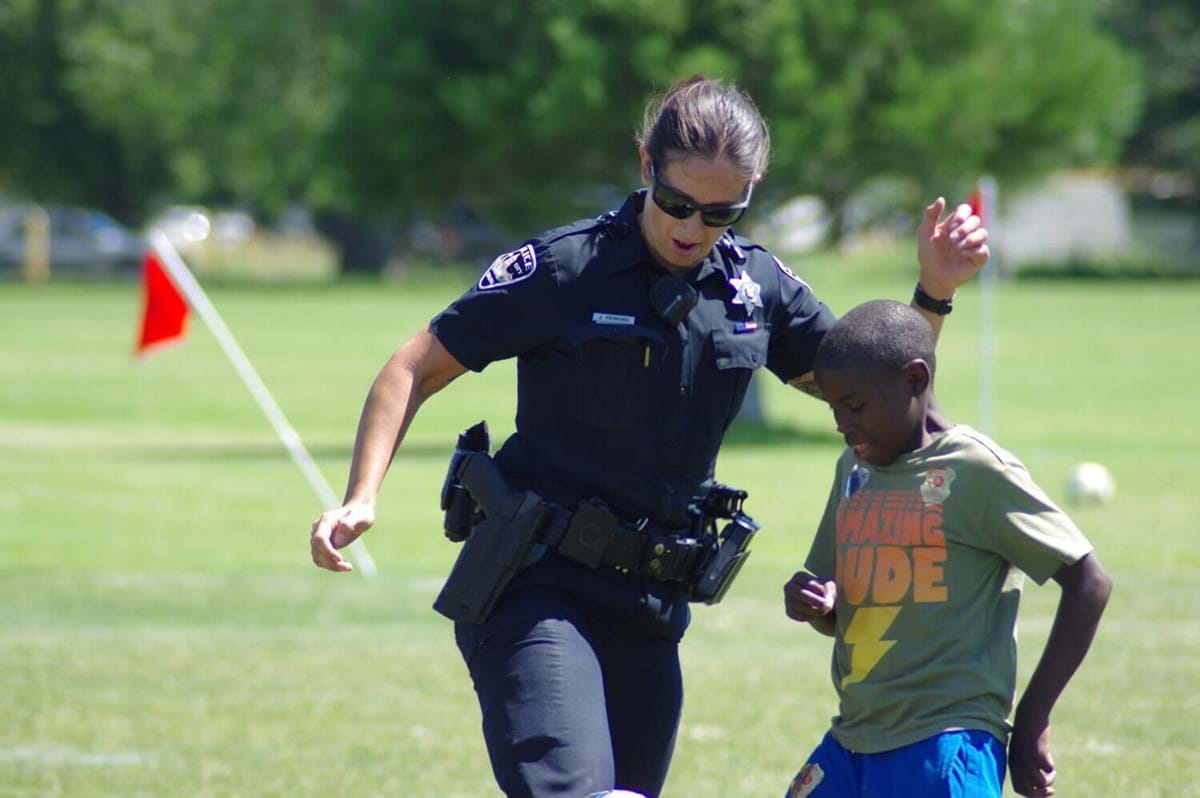 Female officer playing soccer with a child