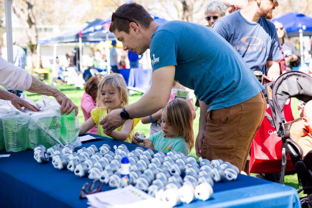 A parent and children participating in a booth at Earth Day.