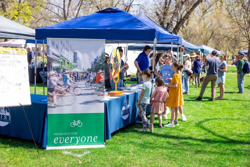 Row of booths at Earth Day with people interacting.