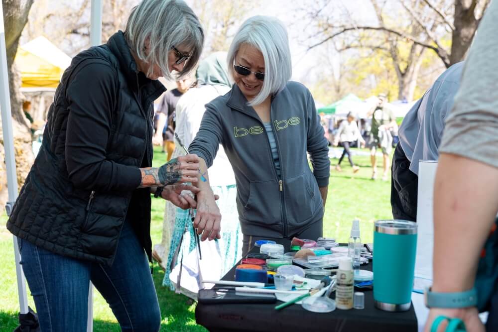 Two women do an experiment in the park at Earth Day Celebration.