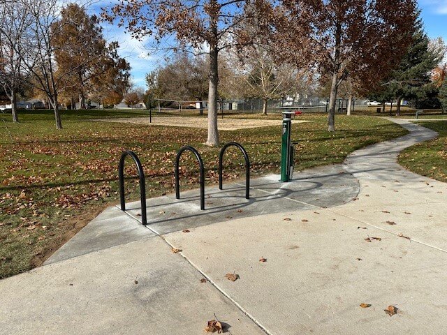 Bike racks and repair station at a park during the day.