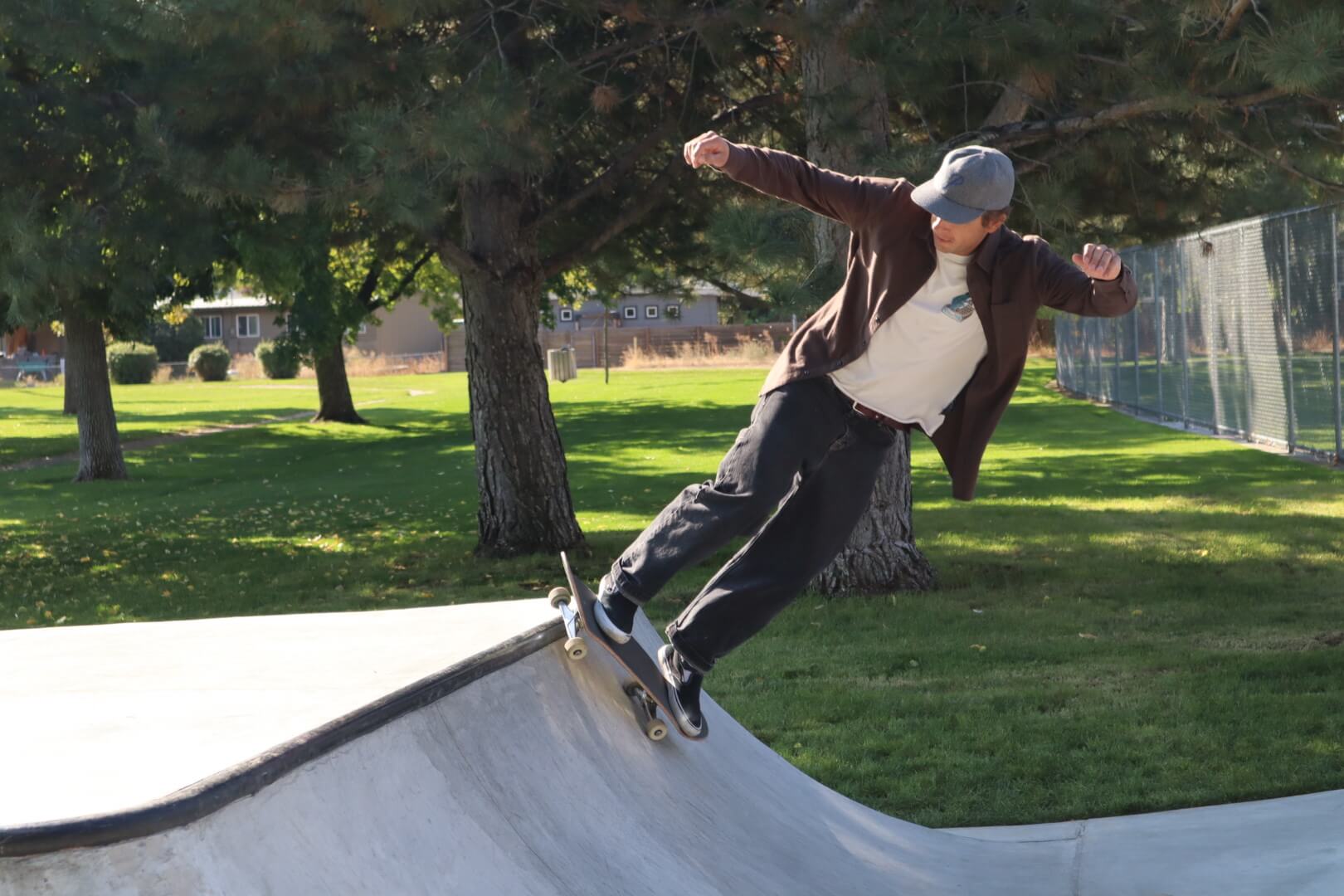 A skateboarder on a ramp in a park during the day.