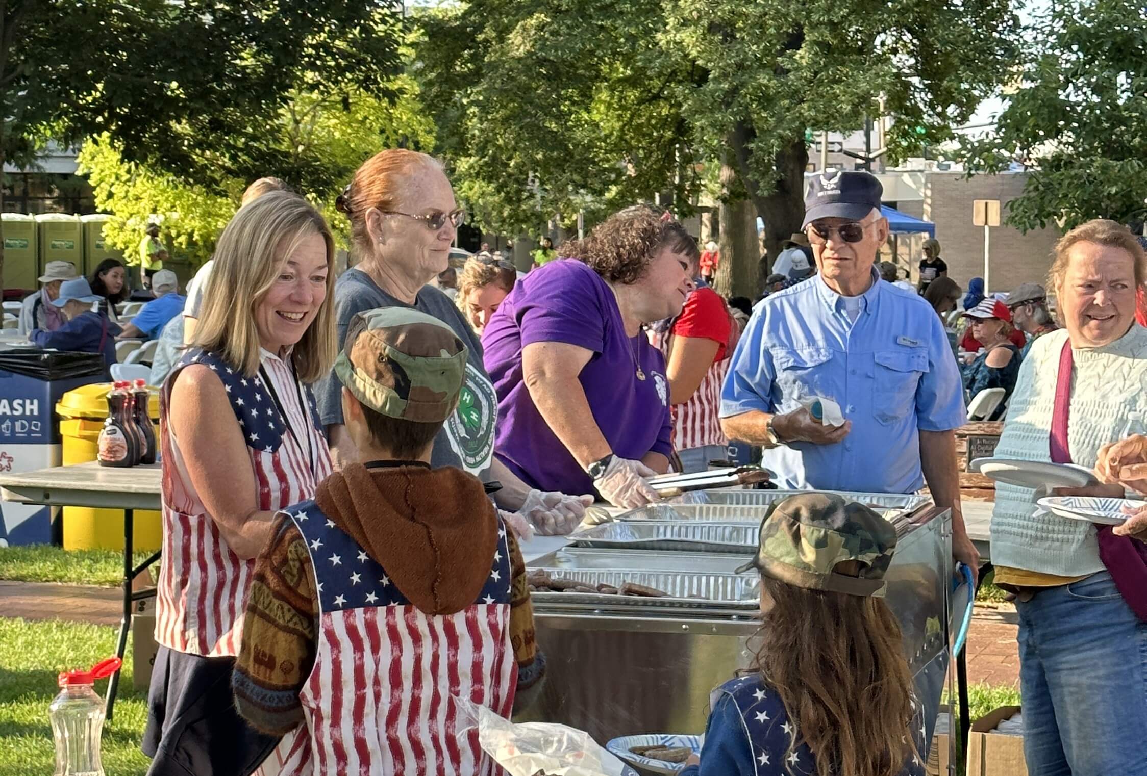 Mayor McLean serving pancakes in a park.