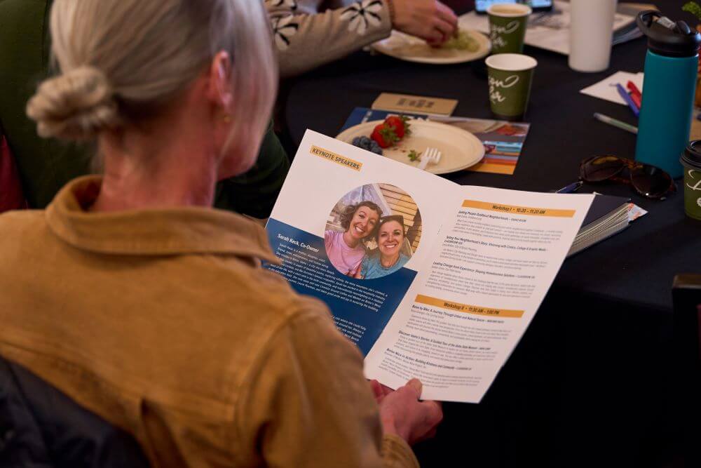 A woman holds printed material while sitting at a meeting.