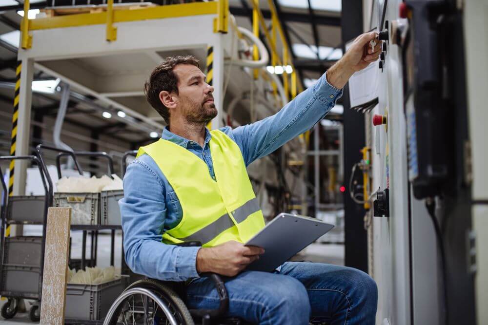 A risk and safety specialist in a wheelchair points at something in a work area.