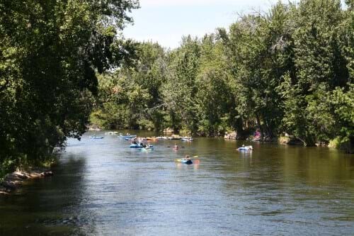 River with trees on side and people floating on rafts, tubes and paddleboards
