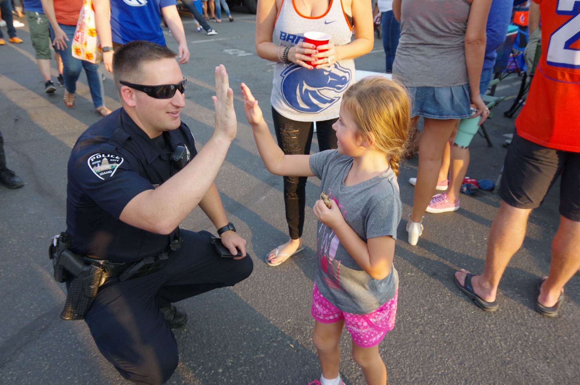 An officer gives a high five to a young child.