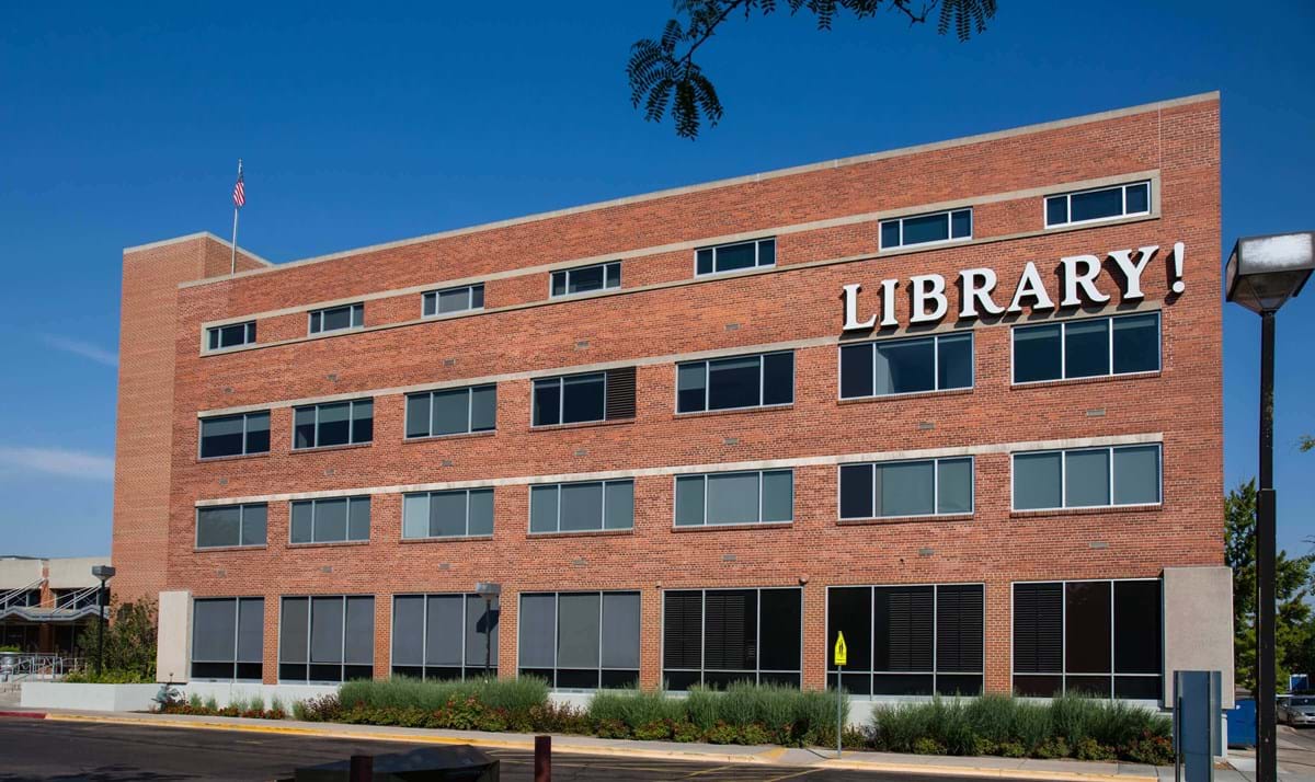 Downtown Library location with brick building and Library! sign on exterior with blue skies