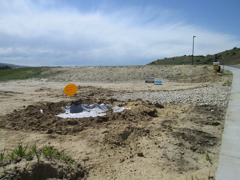 Dirt lot with a clear area labeled "concrete washout" that is lined with a poly lining