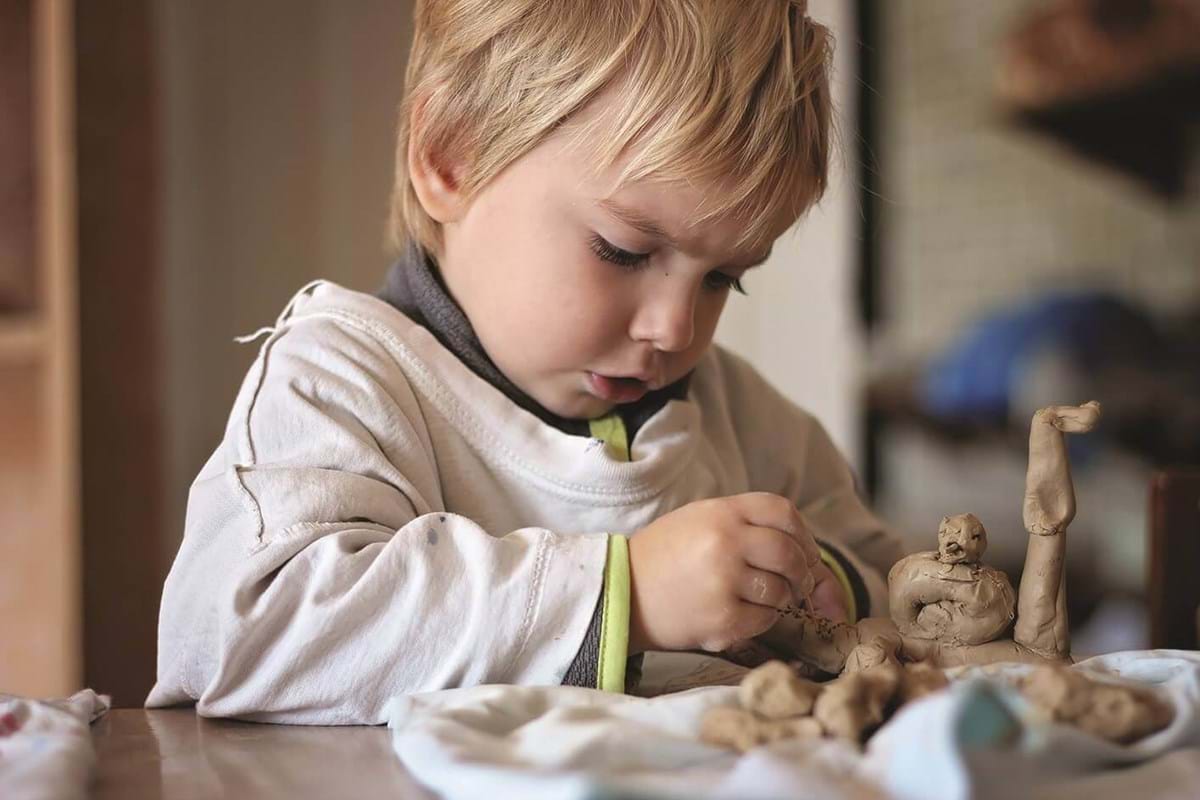 young boy enjoying a clay art class